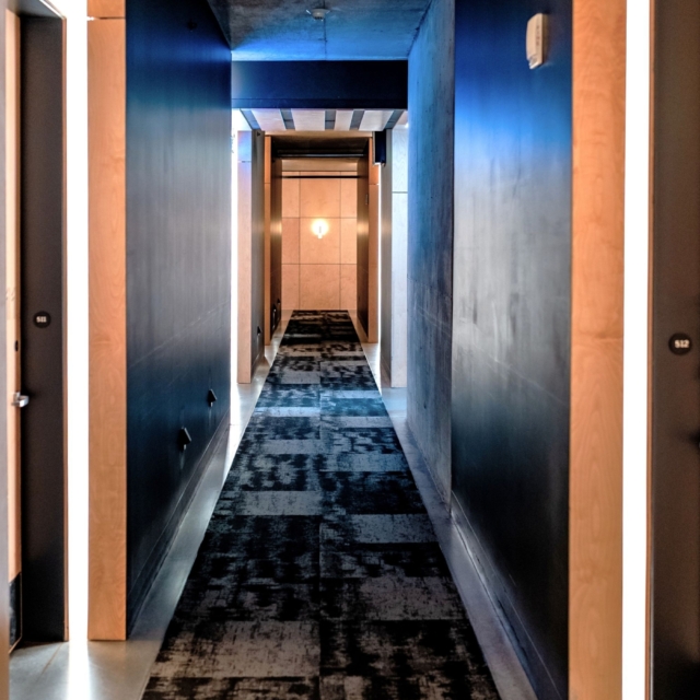 A long hallway with blue walls and black and white carpet.