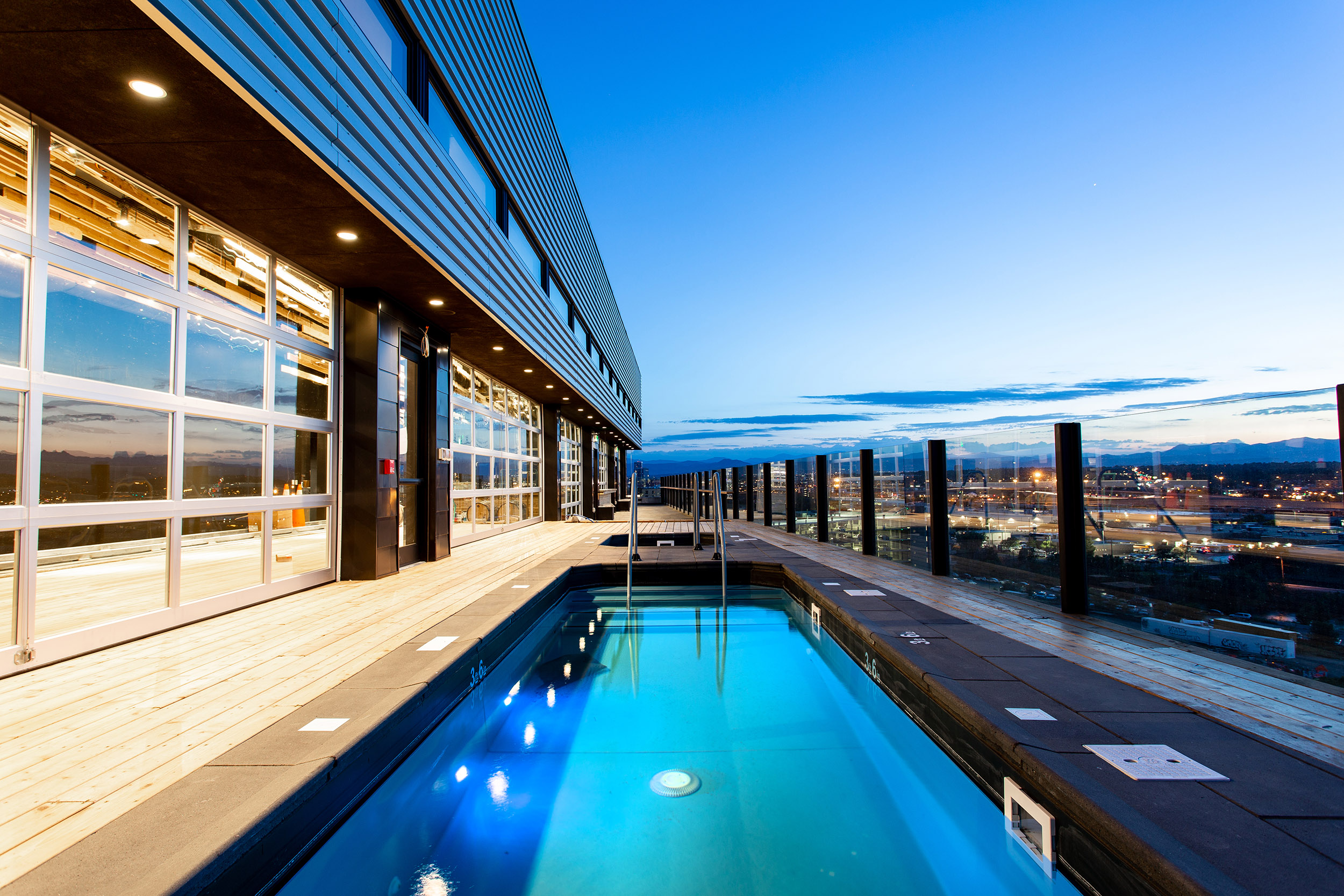 A rooftop pool with a glass railing and city view