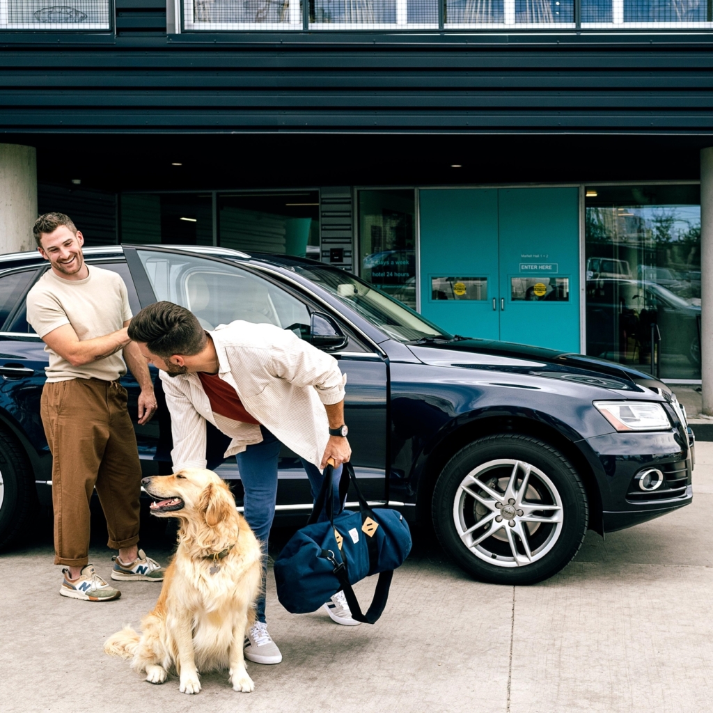 dog and parents by parked car